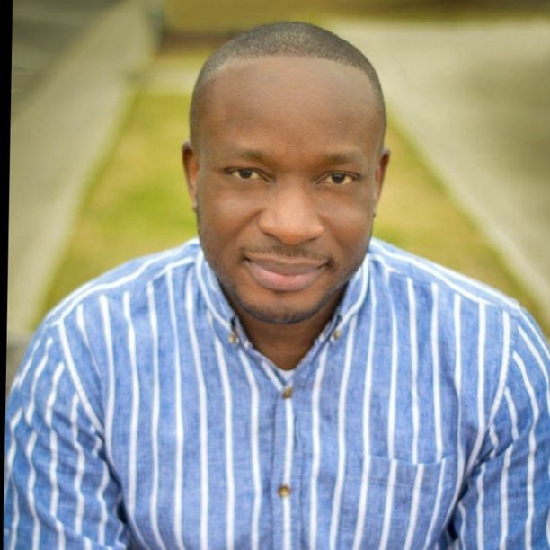 Man in blue and white striped shirt smiling at camera