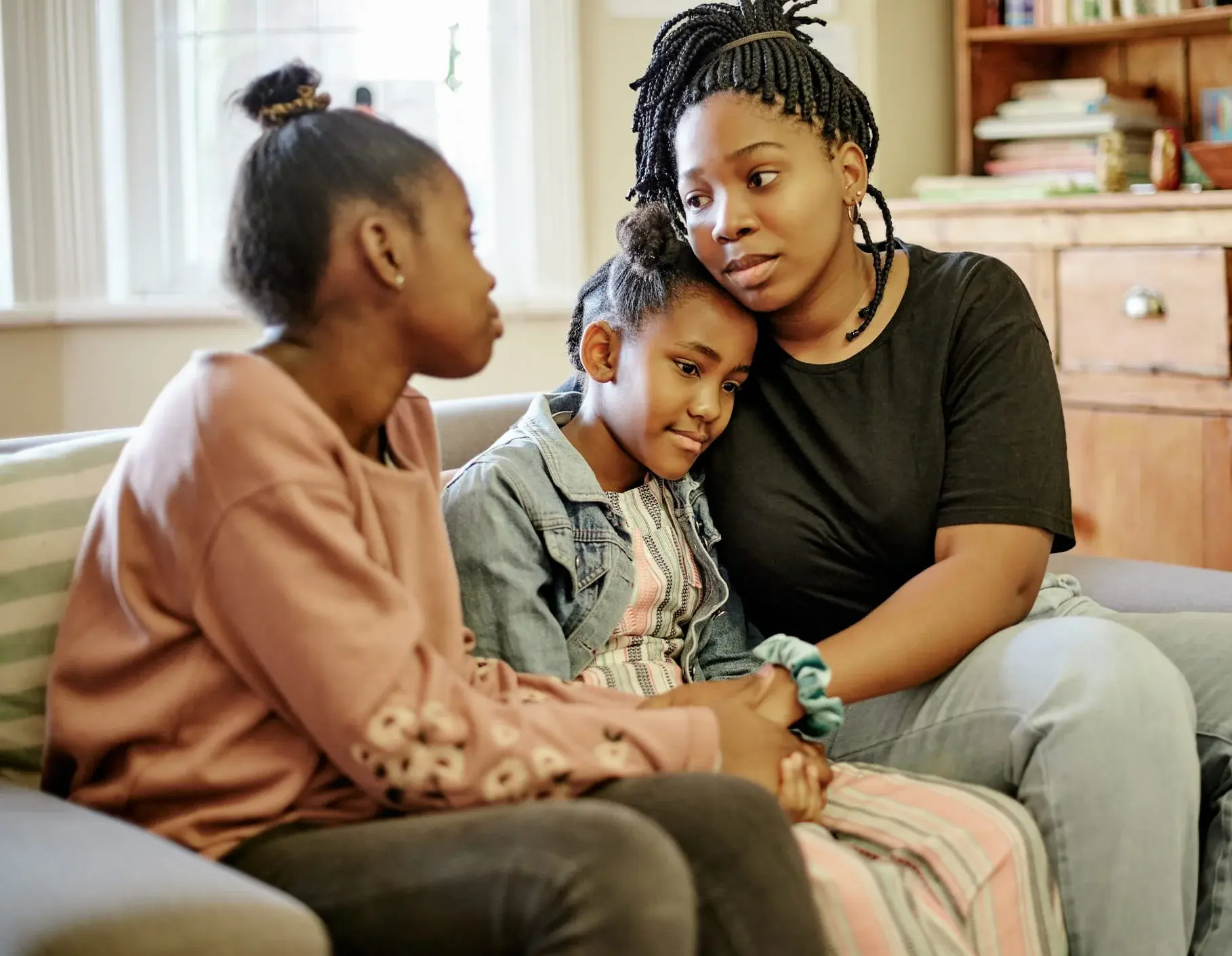 Three children sitting together, one comforting a child in the middle