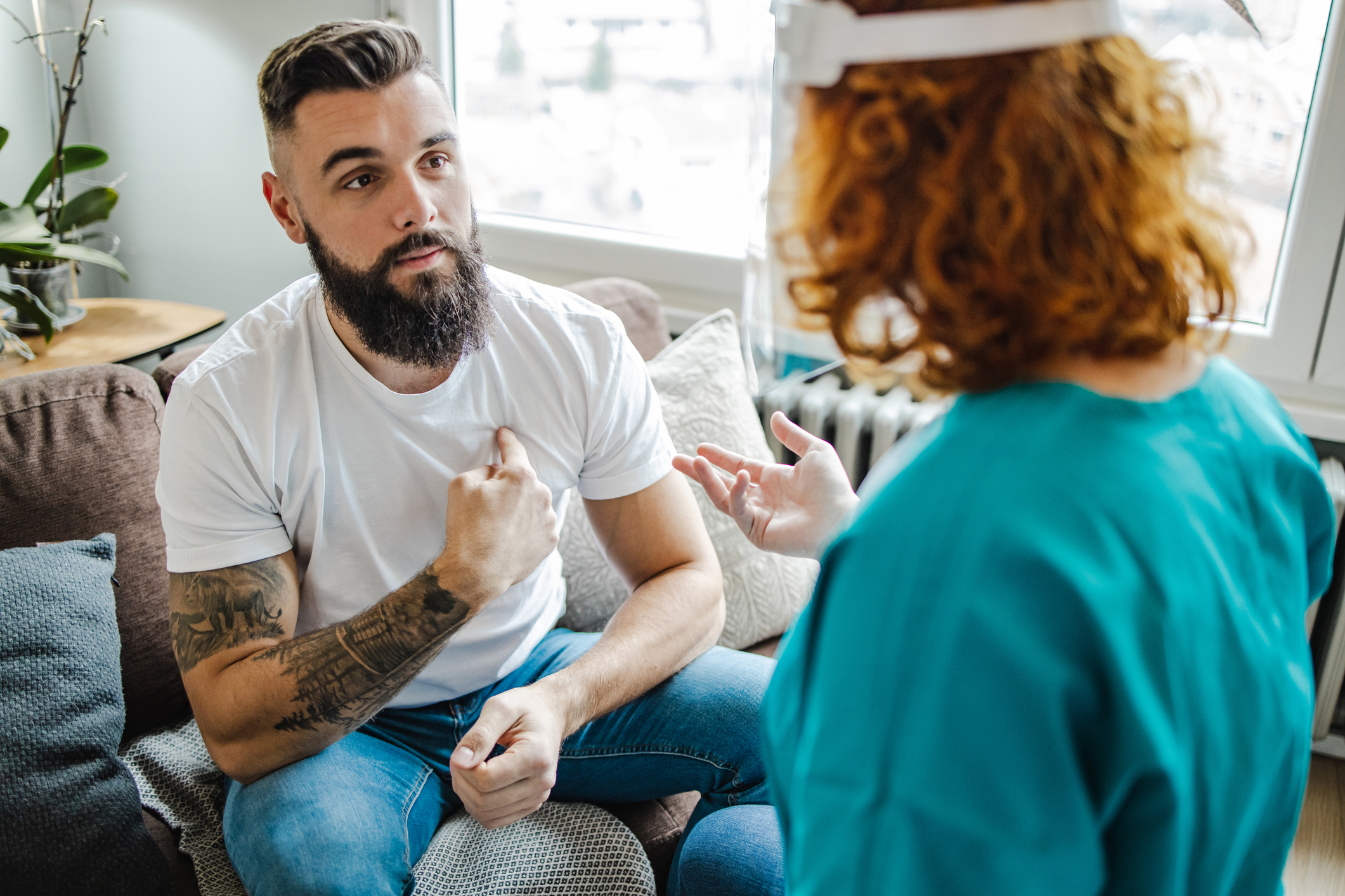 Nurse consulting with a man in a living room setting