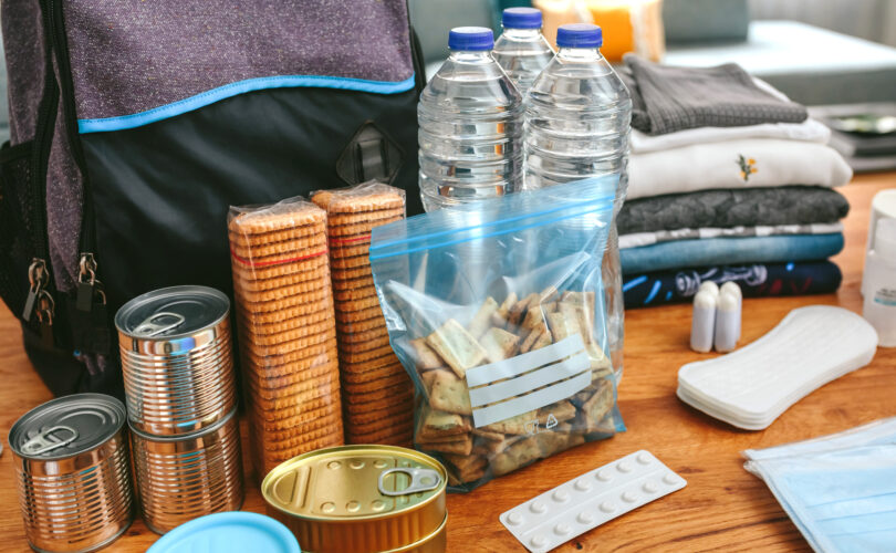 Emergency supplies including water bottles, canned food, crackers, clothes, and medication