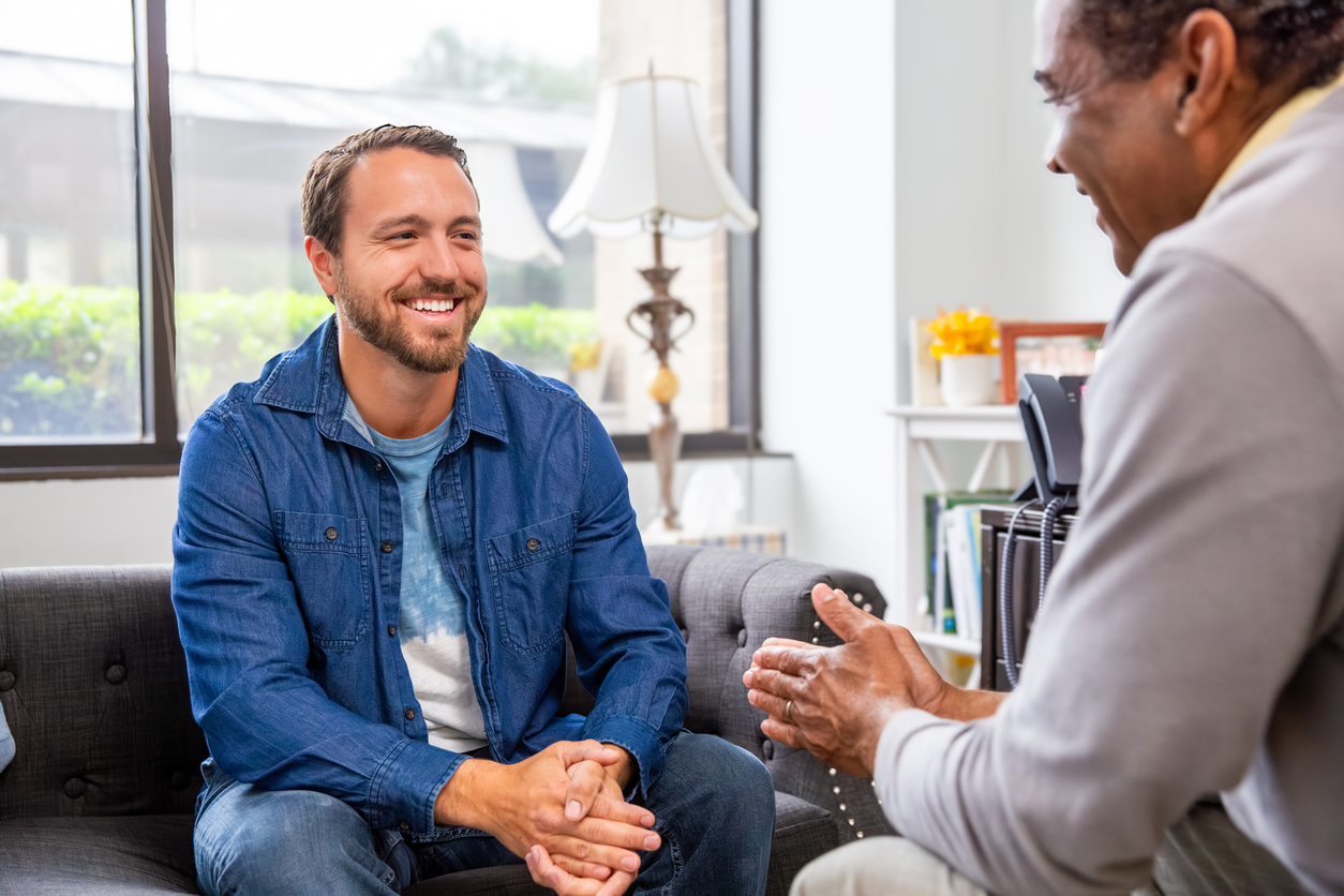 Young man smiling during a counseling session on a sofa
