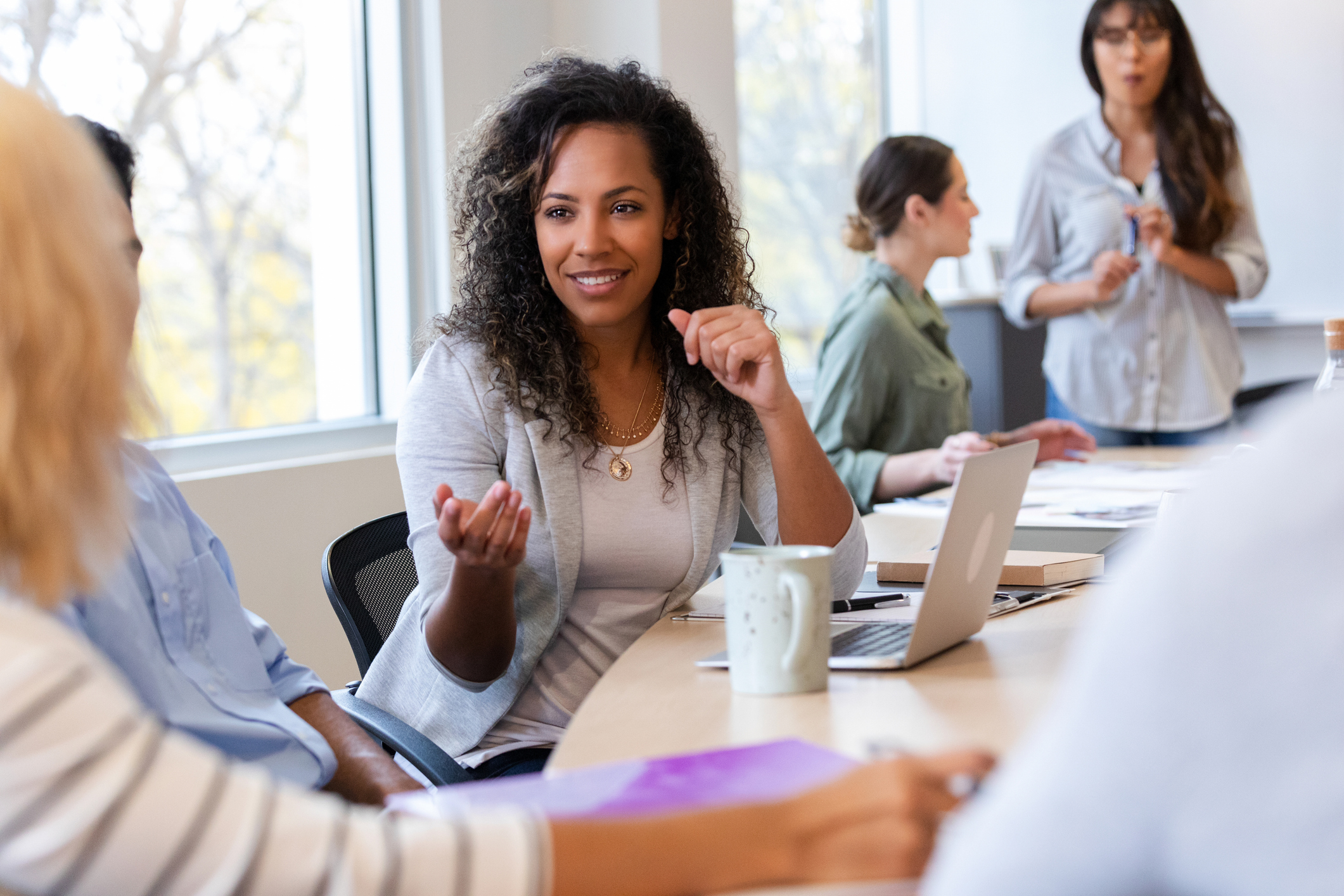 Woman gesturing while discussing ideas with colleagues in meeting