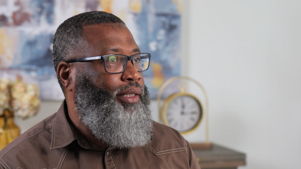 Middle-aged man with gray beard and glasses in indoor setting