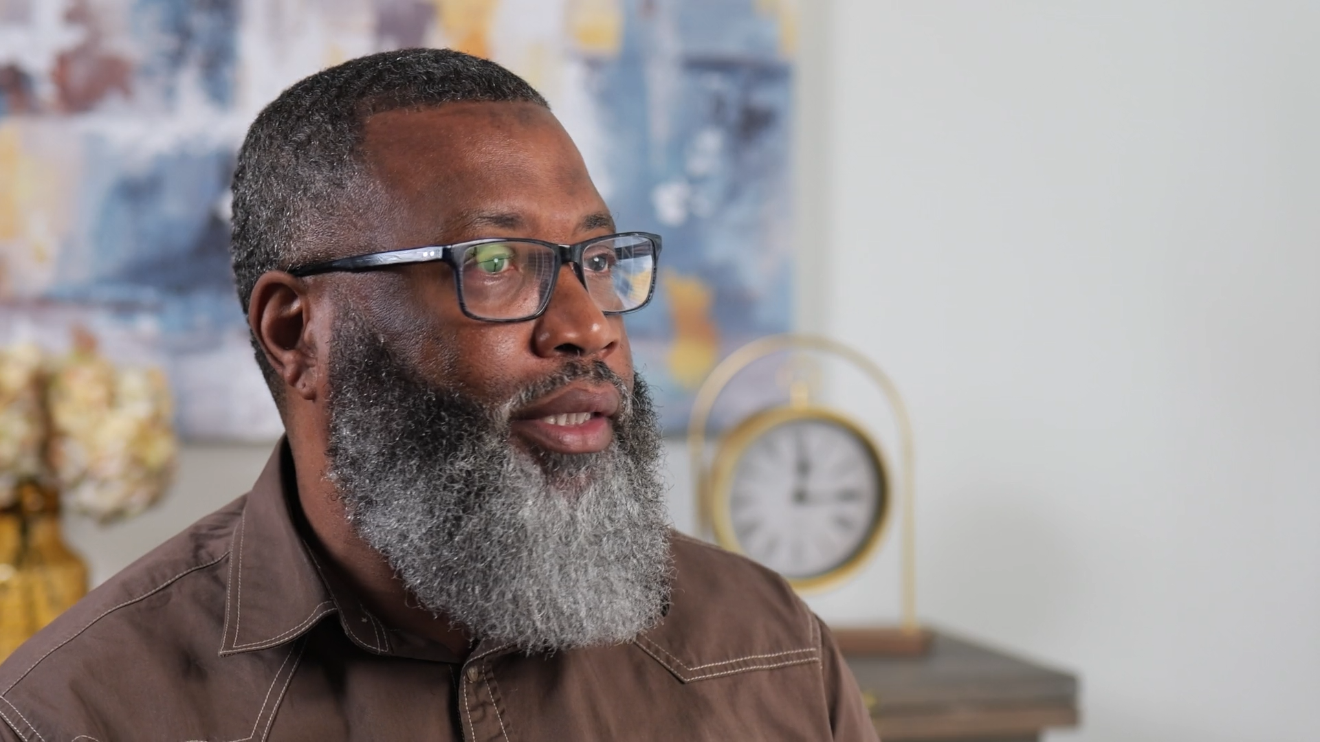 Middle-aged man with gray beard and glasses in indoor setting