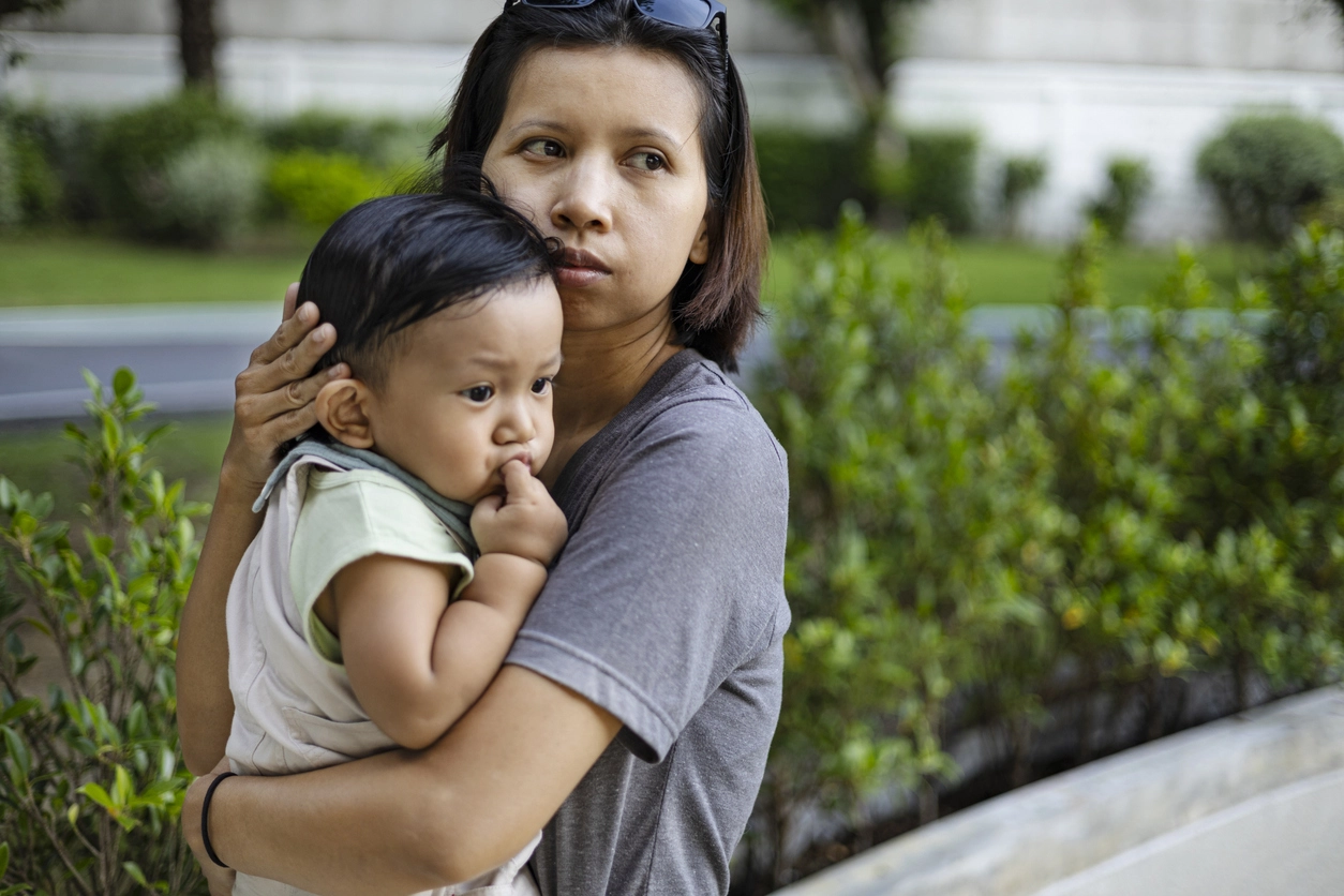 Mom looking concerned while holding her child on a walk outside